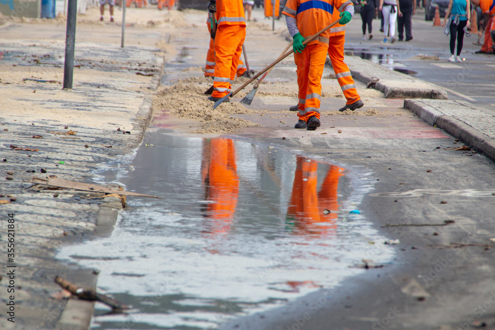 cleaning workers removing sand from the Leblon beach boardwalk in Rio de Janeiro cleaning workers removing sand from the Leblon beach boardwalk in Rio de Janeiro