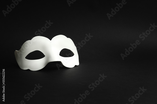 White masquerade mask on a black background