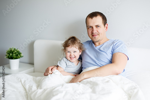 happy father and little daughter sitting on bed