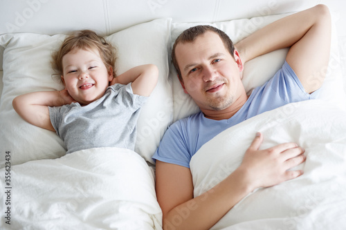 top view of happy father and little daughter waking up at home