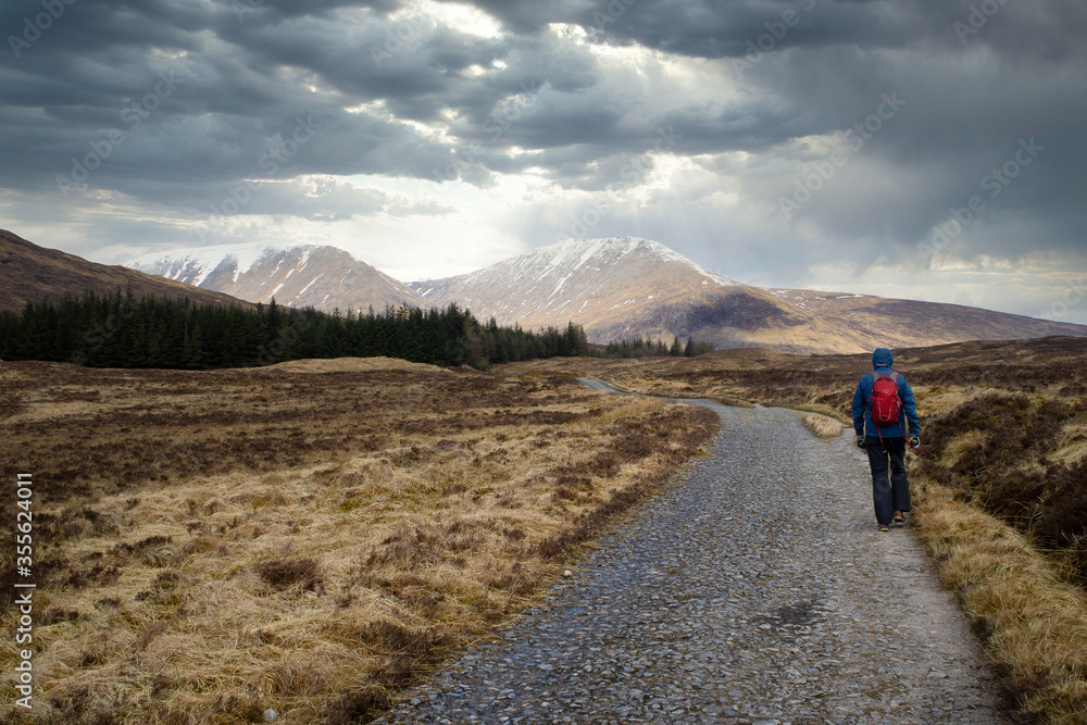 Bridge of Orchy (Scotland), April 2019. Hiker walking towards the sun on the West Highland Way.