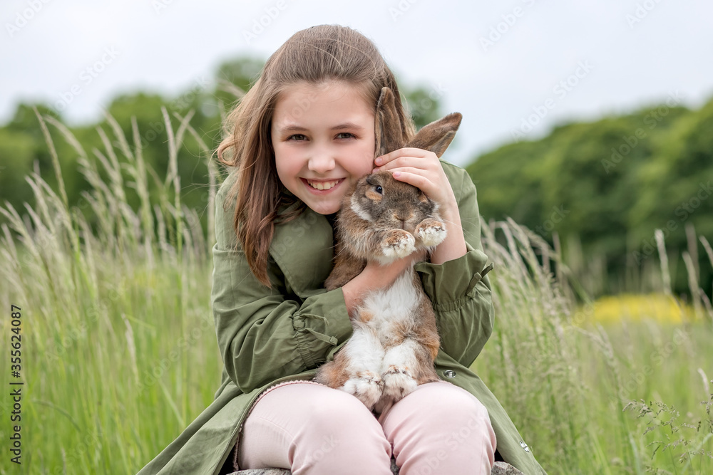 Cute red haired domestic rabbit. The girl holds a fluffy animal in her arms. Pet care concept Cute red haired domestic rabbit. The girl holds a fluffy animal in her arms. Pet care concept