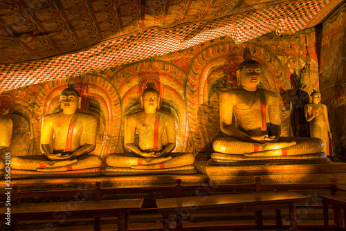 Three ancient sculptures of a seated Buddha in the Buddhist cave temple Rangiri Dambulu Raja Maha Viharaya. Dambulla, Sri Lanka photo