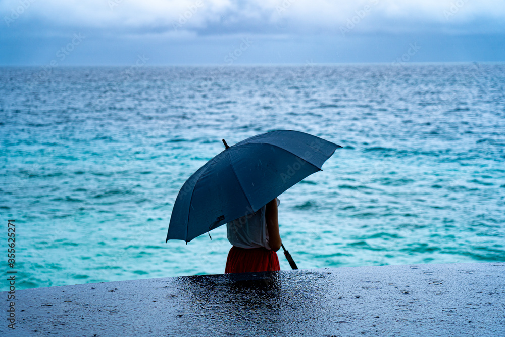 海上で傘をさす女性