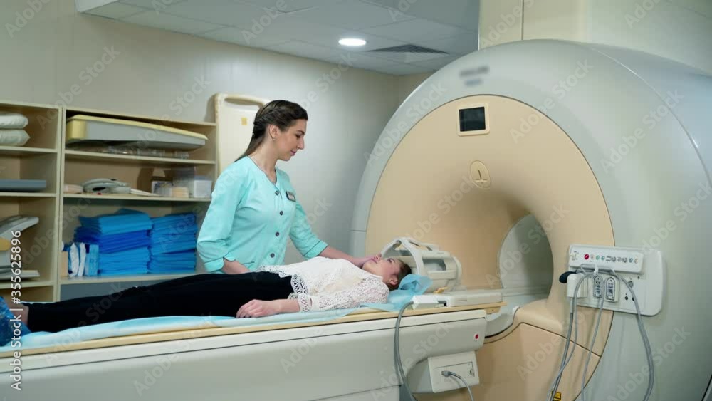 Magnetic resonance image device in hospital. Female patient lying in MRI machine and medical worker controls the procedure. Advanced medicine. Magnetic resonance image device in hospital. Female patient lying in MRI machine and medical worker controls the procedure. Advanced medicine.