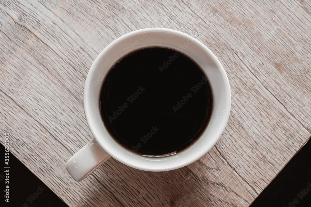 Top view of black coffee in white cup on wooden table. Brown tone photo Top view of black coffee in white cup on wooden table. Brown tone photo