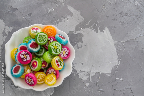 Colorful fruit candy sweets close up. different tastes and drawings of fruits on candies in boul isolated on gray background