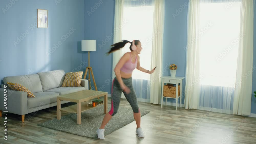 Young fit woman in sport outfit has great time at home, dancing after daily workout, enjoying her favorite music, positive and energetic. Young fit woman in sport outfit has great time at home, dancing after daily workout, enjoying her favorite music, positive and energetic.