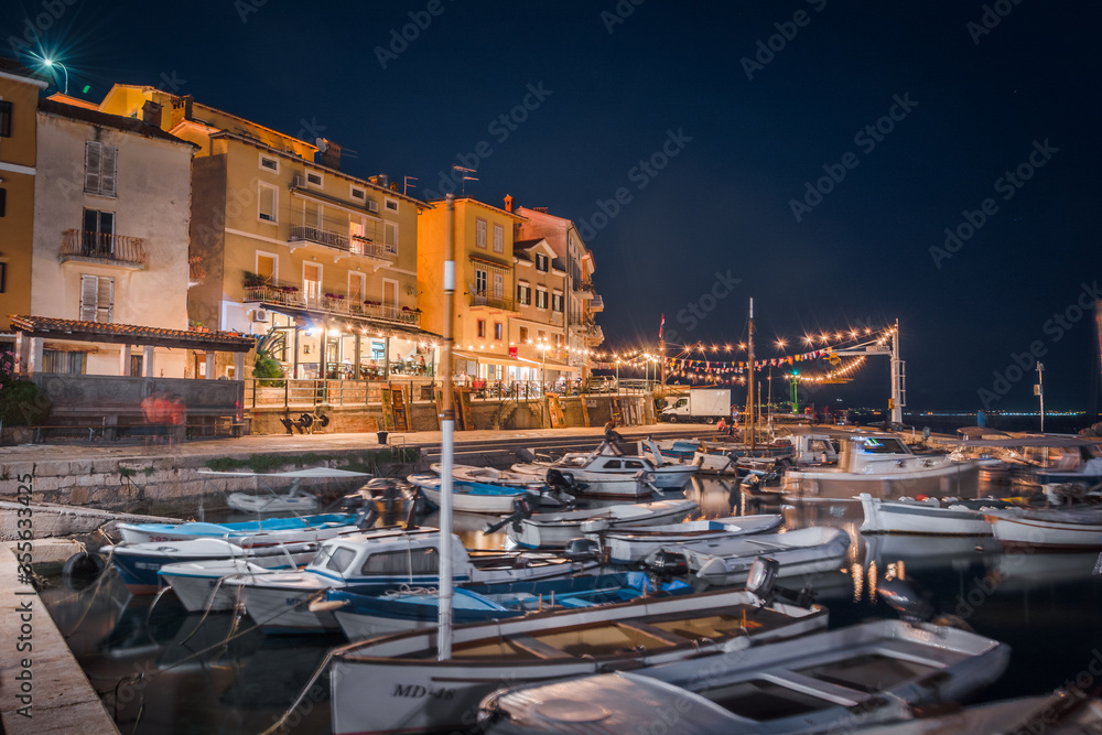 Small fishing boats docked in the beautiful small harbour sea port. Small fishing village in Adriatic sea by night. Vacation in Croatia, Europe