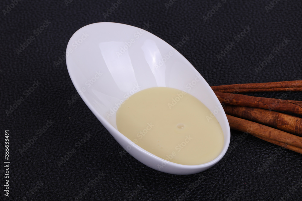 Condenced milk in the bowl with sinnamon and pastry Condenced milk in the bowl with sinnamon and pastry