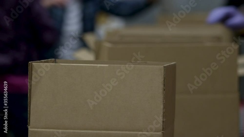 Food donation boxes going down a line of gloved volunteers during the COVID-19 pandemic