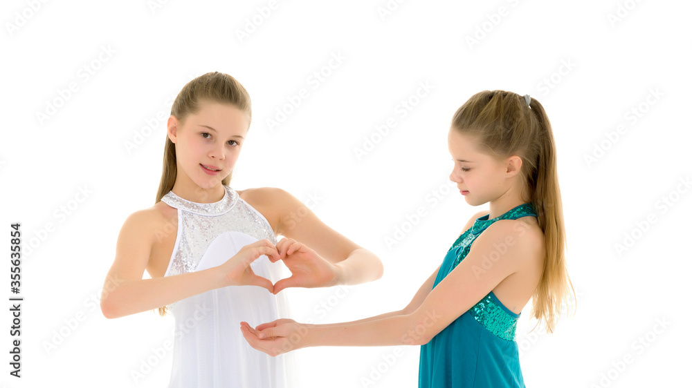 Two adorable girls gymnasts folded palms in the shape of a heart Two adorable girls gymnasts folded palms in the shape of a heart