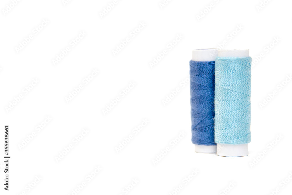 Blue and blue sewing threads on a white background. Blue and blue sewing threads on a white background.