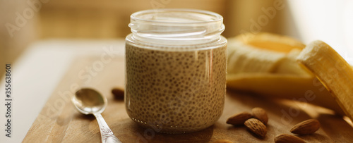 Dessert bowl of tasty chia seed pudding and banana, almond on wooden table on white background. Banner for website