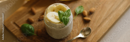 Vegan Chia Pudding with Banana and almond on wooden background. Vegan, morning, breakfast, healthy eating concept. Banner for website