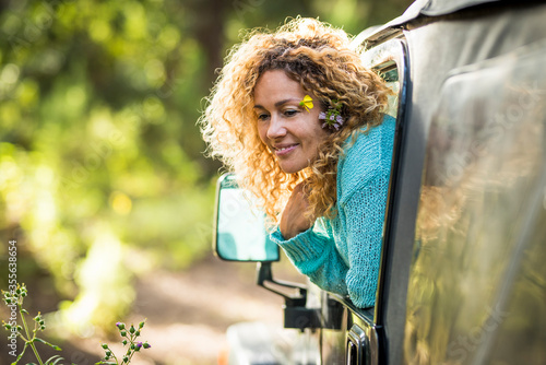 Beautiful travel concept adult woman enjoy the forest sit down inside a car and outside the window - adventure and alternaive nature love lifestyle for happy people in outdoor leisure vehicle activity photo