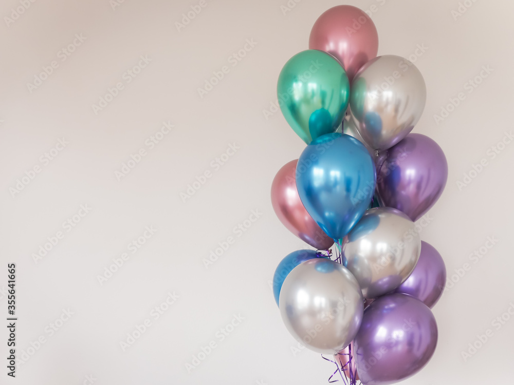 multicolored balloons on the background of a light wall. left-oriented image