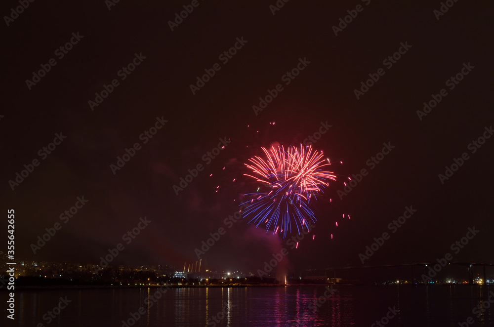 Beautiful firework on night sky in tromsoe city with bridge, cathedral and colorful reflection on the cold fjord water surface on new years eve Beautiful firework on night sky in tromsoe city with bridge, cathedral and colorful reflection on the cold fjord water surface on new years eve