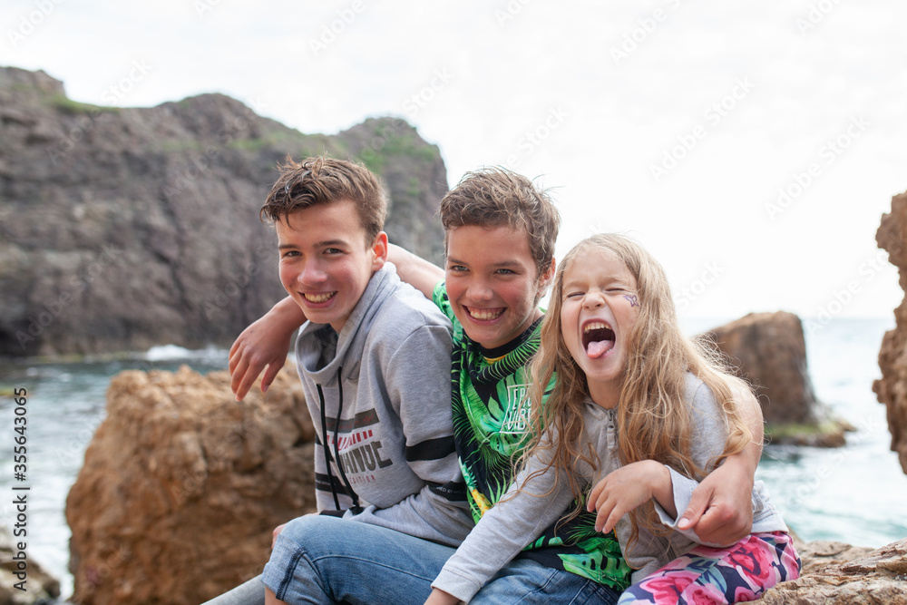 Portrait of happy brothers and sisters on the background of the sea, children walk by the sea Portrait of happy brothers and sisters on the background of the sea, children walk by the sea