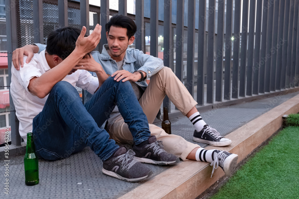 Young Asian man supporting sad drunk friend Young Asian man supporting sad drunk friend