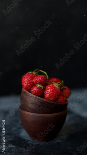 Bowls with ripe fresh strawberry on dark background