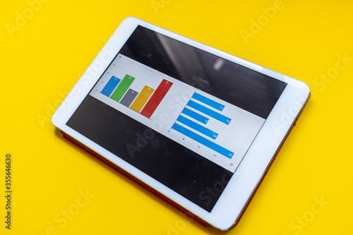 Tablet with diagram and report on a yellow background. Office environment. Business concept.