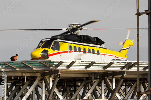 A helicopter on top of a offshore oil-platform transporting roughnecks  photo