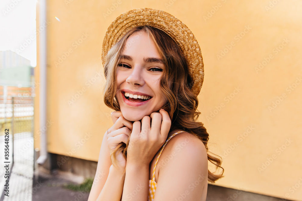 Fascinating curly woman in elegant hair smiling on yellow background. Relaxed european girl laughing in sunny morning.