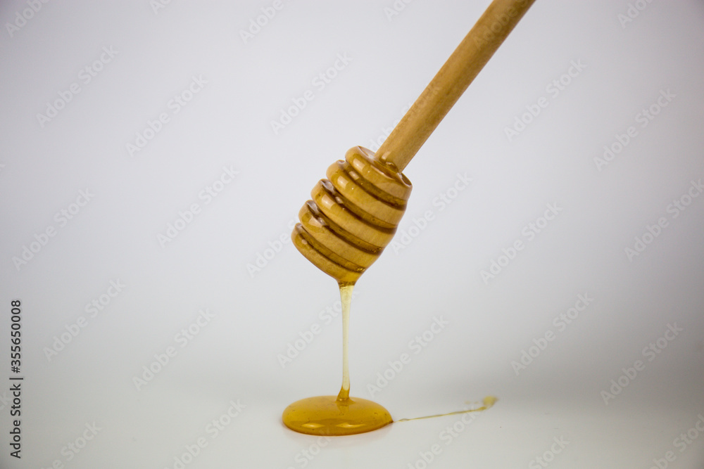 Honey dripping isolated on a white background. Natural remedy and prevention for diseases Honey dripping isolated on a white background. Natural remedy and prevention for diseases