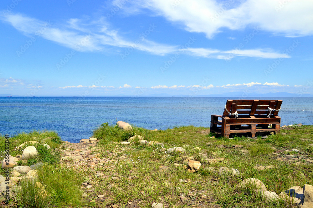 Wooden old bench without people on the background of the Japanese sea on a summer day Wooden old bench without people on the background of the Japanese sea on a summer day