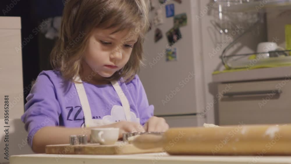Charming little girl making biscuits at the kitchen table Charming little girl making biscuits at the kitchen table
