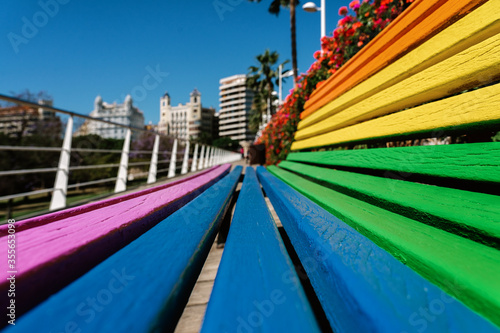 Perspective of a wooden bench with the colors of the LGTB rainbow in the city of Valencia, Spain. Concept of equality, respect. © JavierBallesterLegua