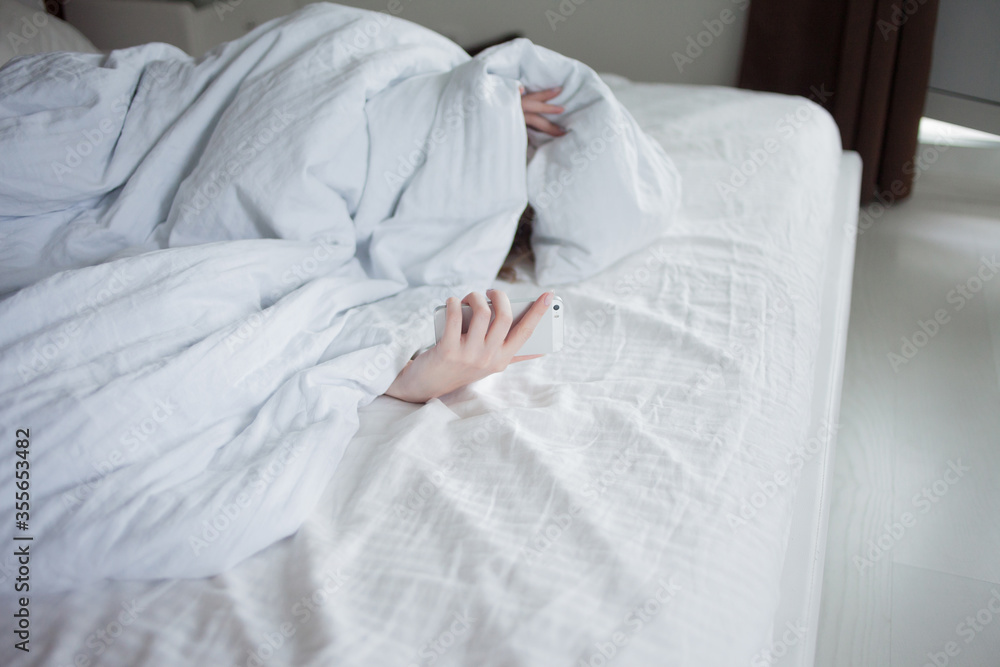 Morning, the woman under the blanket, turns off the alarm clock Morning, the woman under the blanket, turns off the alarm clock