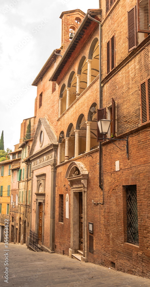 Gloomy narrow medieval street in  Italian city of Siena