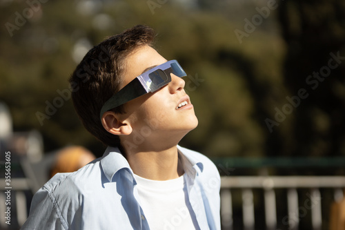 Canvas Print impressed teenager looking at a sun eclipse with eclipse glasses