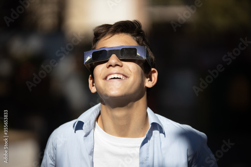 smiling boy watching an eclipse of the sun with eclipse glasses photo