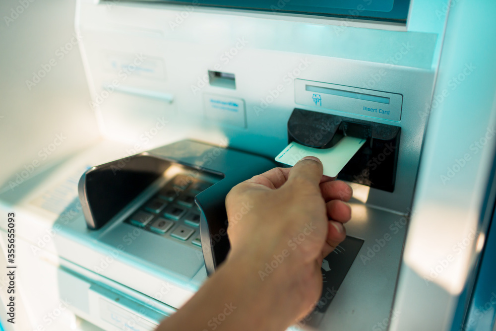 Man's Hand Using Card To Withdraw Money. Close up image of a human hand inserting a credit card in the ATM. Hand inserting debit card into an ATM machine. Horizontal shot. Man's Hand Using Card To Withdraw Money. Close up image of a human hand inserting a credit card in the ATM. Hand inserting debit card into an ATM machine. Horizontal shot.