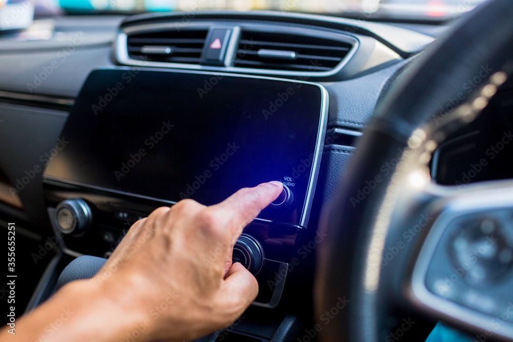 Selective focus to driver's finger touch on power button the smart monitor screen at the console in the car. The concept of smart car.