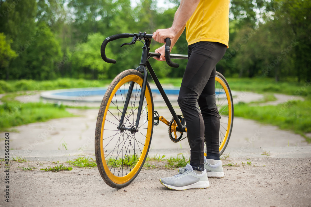 A young Man stopped to rest With his Bicycle in a public Park. A young Man stopped to rest With his Bicycle in a public Park.