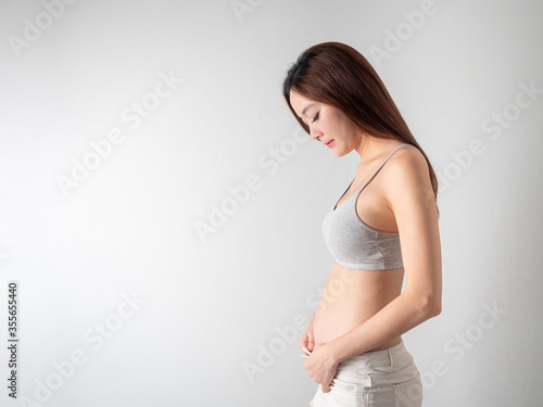 Studio Portrait of 2 months Pregnant Woman on white background.