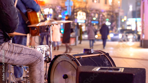 Traditional music street Performers, playing some instruments. Street musicians with a guitar and drums on the night street of the big city © Maksim