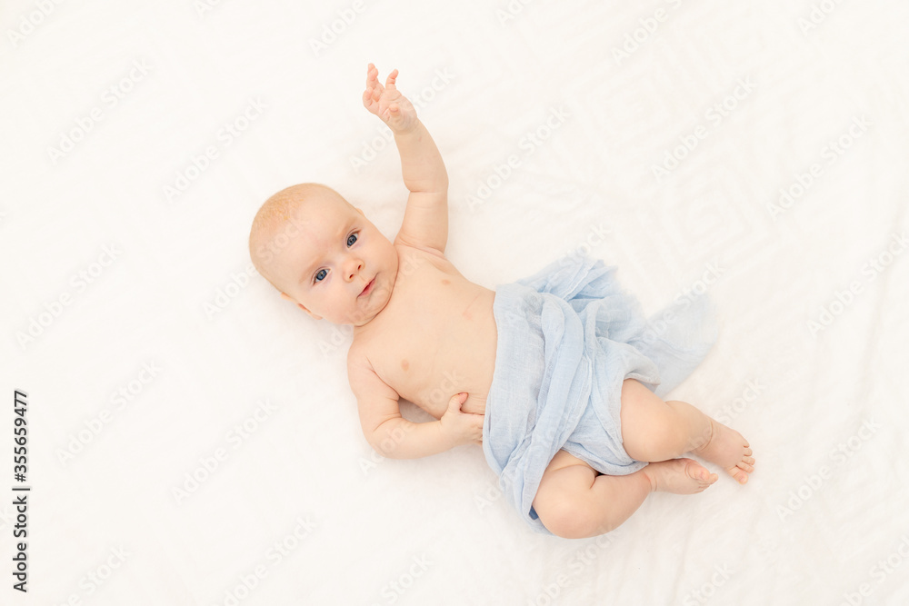 a naked baby is lying on a white background. Bedding for children. 6 months. Healthy baby in the crib. Space for text a naked baby is lying on a white background. Bedding for children. 6 months. Healthy baby in the crib. Space for text