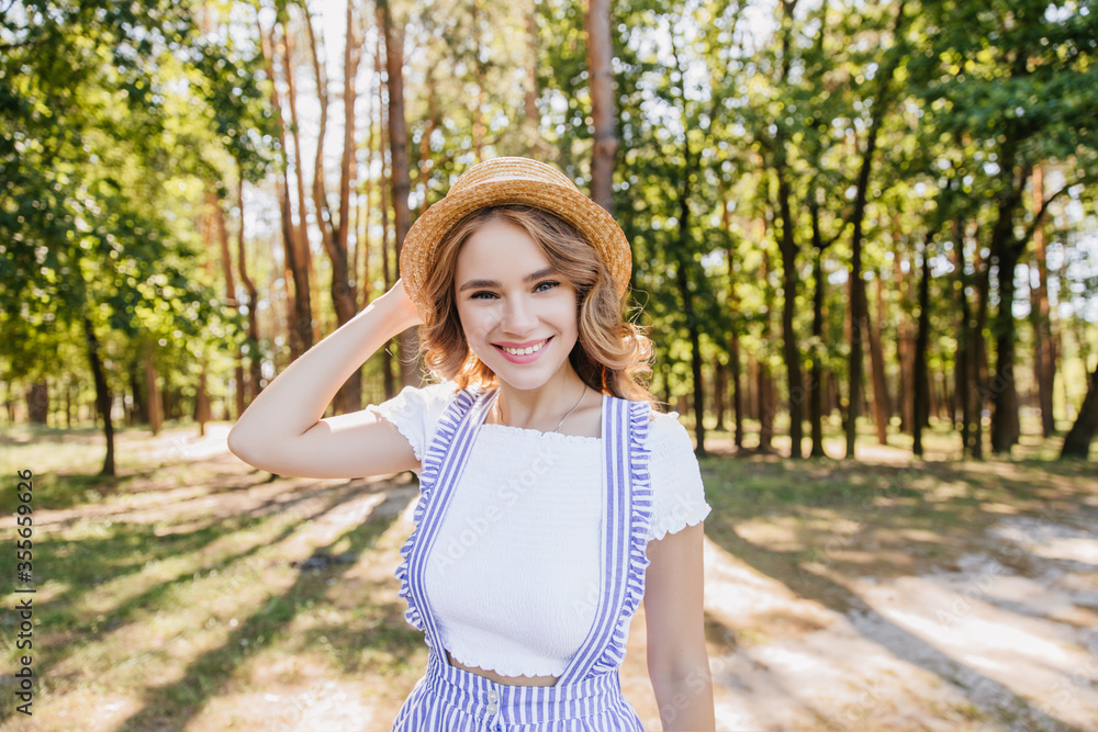 Stunning curly girl posing in forest with beautiful smile. Outdoor shot of winsome young lady having fun in park in sunny morning. Stunning curly girl posing in forest with beautiful smile. Outdoor shot of winsome young lady having fun in park in sunny morning.