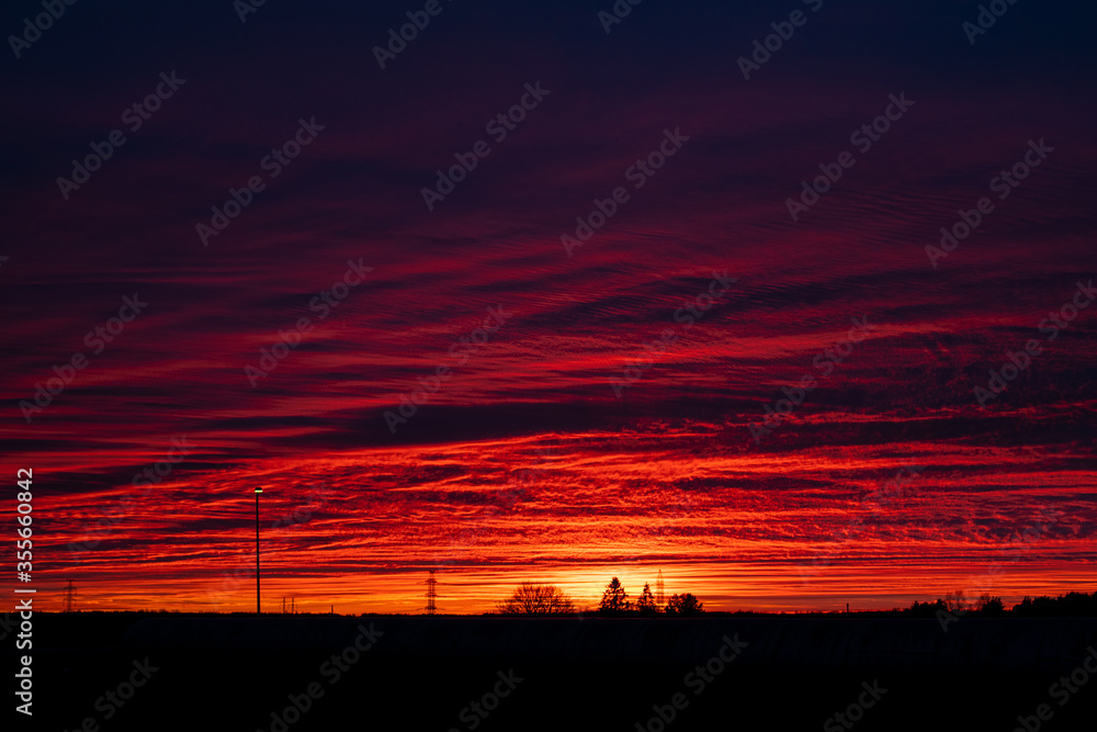 Blurred background. Natural Sunset Over Field Or Meadow. Bright Dramatic Sky And Dark Ground.  