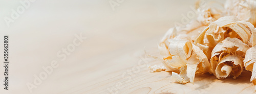 Large shavings from spruce wood close-up on a board of spruce blurred background. Macro photography with constant light. Panoramic banner with copy space for text. Front view