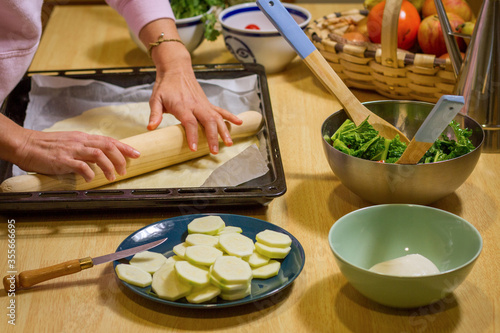Close up of female hands using a rolling pin to make a pizza base.