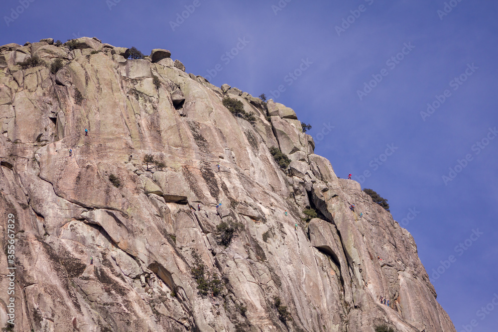 Pico de la Miel, Madrid, Spain. General view of Rock climbers climbing granite rock formation called The Honey Peak. Pico de la Miel, Madrid, Spain. General view of Rock climbers climbing granite rock formation called The Honey Peak.