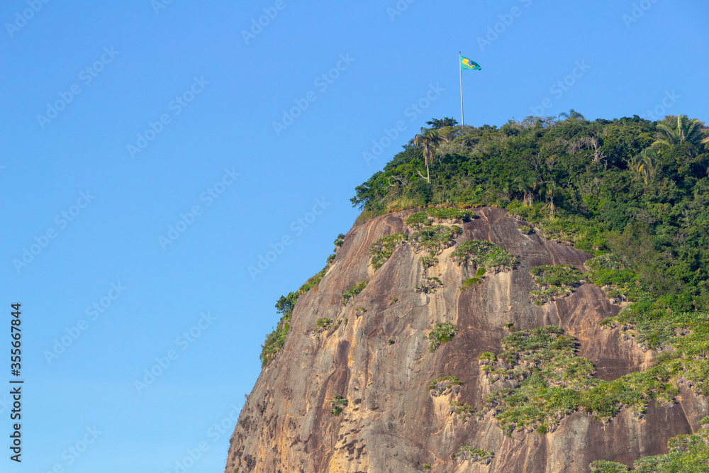 Fototapeta premium Helm stone with Brazil flag on top, seen from the helm beach in Rio de Janeiro.