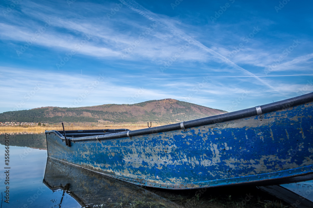 Low angle small blue abandoned fishing boat. Lake Cerknica, one of the largest intermittent lakes in Europe. Low angle, wide shot