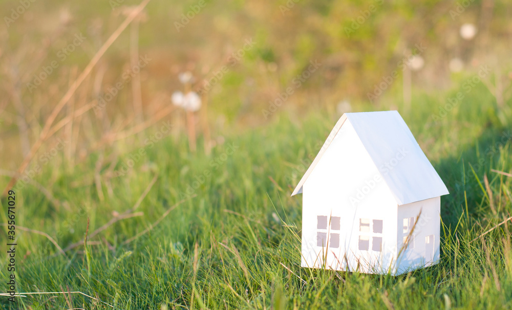 White paper miniature house. On the green grass. The concept of buying or building a house White paper miniature house. On the green grass. The concept of buying or building a house